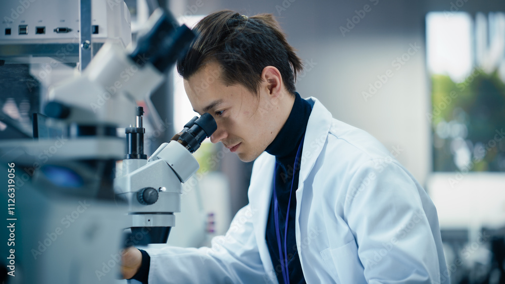 Poster portrait of a young graduate student working in a laboratory, using advanced microscope, writing dow