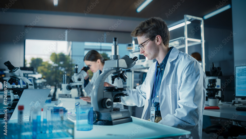 Poster Portrait of a Young Smart Scientist Working in a Laboratory, Using Advanced Microscope, Writing Down Research Data in a Paper Notebook. Caucasian Biotechnology Specialist Using Modern Tools