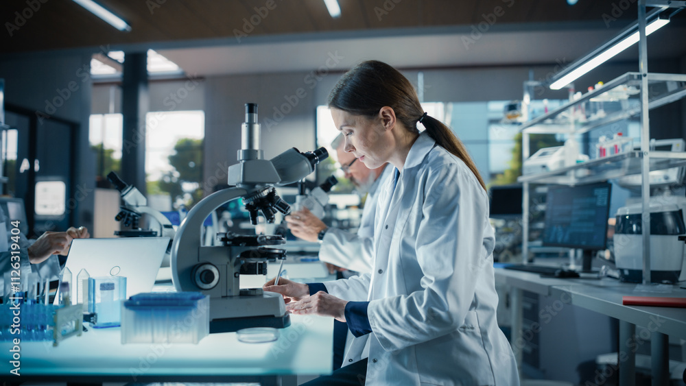 Poster Female Bioengineer Looking at DNA Samples Under a Microscope in a Modern Applied Science Laboratory. Portrait of a Young Lab Engineer in White Coat Working with Colleagues