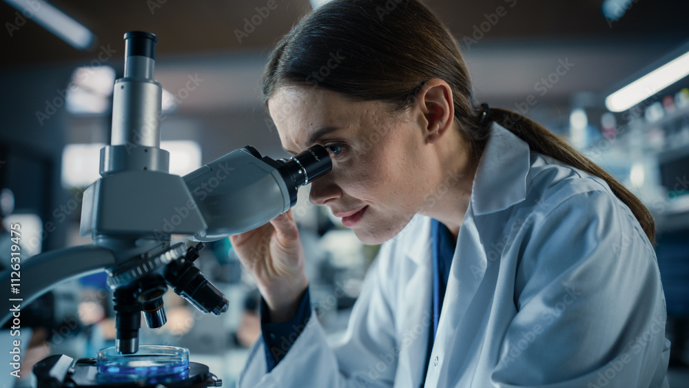 Poster Portrait of a Beautiful Caucasian Student Working on a Research Project in College. Medical Research Scientist Looking at Biological Samples Under a Microscope in an Applied Science Laboratory