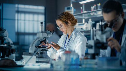 Hisplanic Female Bioengineer Looking at DNA Samples Under a Microscope in a Modern Applied Science...