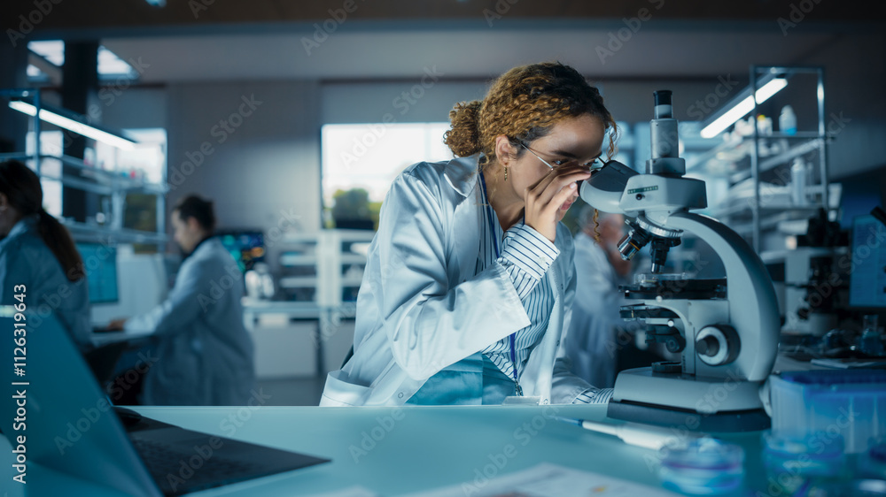 Poster Portrait of a Smart Multiethnic Student Working on a Research Project in School. Medical Research Scientist Looking at Biological Samples Under a Microscope in an Applied Science Laboratory