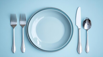 Elegant place setting with light blue plates and silverware on a pastel blue background.