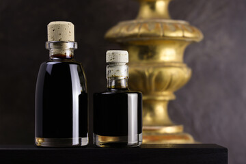 Due bottigliette di aceto balsamico, condimento tipico di Modena, isolate su fondo scuro, primo piano
