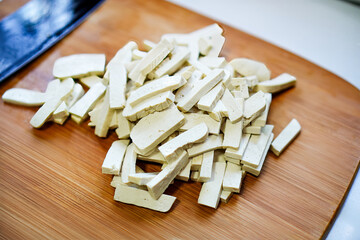 Close-up of sliced ​​soft tofu on a wooden cutting board for use as a food ingredient in a kitchen.