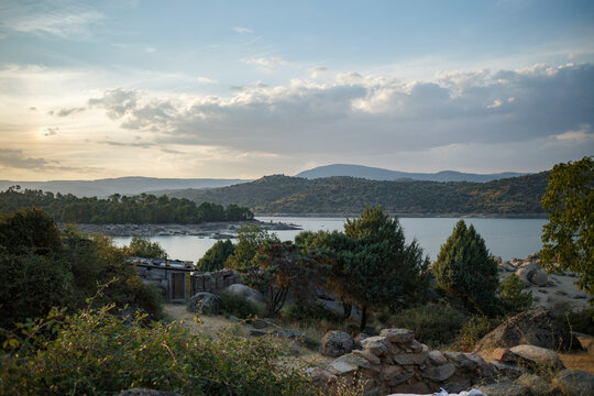 Scenic overlook of a reservoir, with hills, trees, and a small structure.  Tranquil landscape at sunset.
