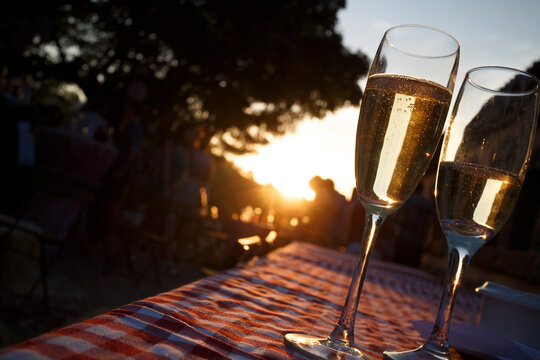 Two champagne flutes at sunset, outdoors on a checkered tablecloth.  Celebration or enjoyment.