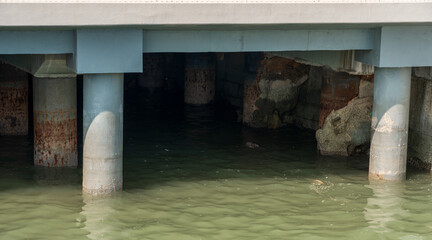 Underneath a Concrete Pier: Structural Elements and Water Reflection