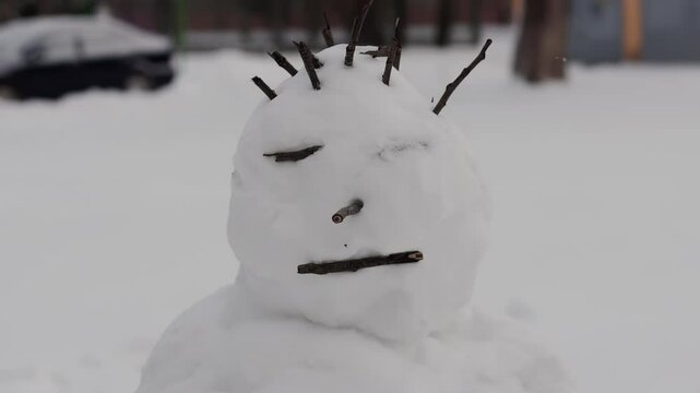 A snowman stands in the yard in the snowy winter, slow motion
