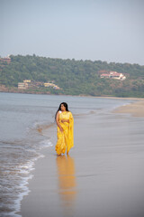 young Indian woman walking on the beach in saree