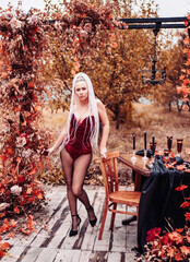 Girl in burgundy bodysuit near autumn arch table and chairs