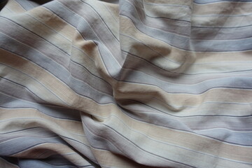 Rumpled light beige, blue and grey striped cotton fabric