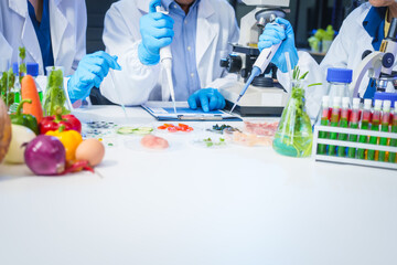 A male scientist and two women conduct plant research in a laboratory.  microscopes, petri...