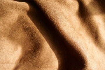 Texture of chocolate brown faux suede polyester fabric in soft folds