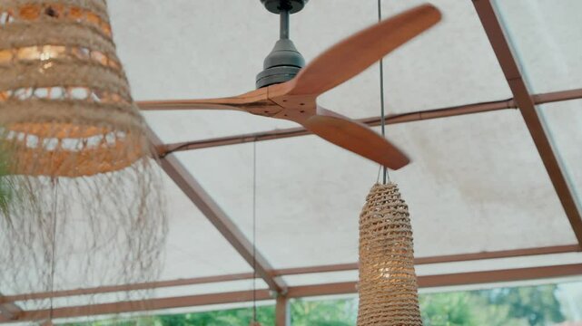 Spinning ceiling fan with woven pendant lights in a shaded outdoor setting