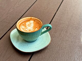 Elegant cup of latte with art on wooden surface