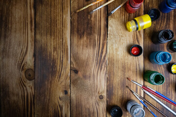 Painting background with different colors of gouache and brushes on a wooden surface