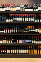 Fototapeta premium Vertical background of wine bottles displayed on shelves in a liquor store.