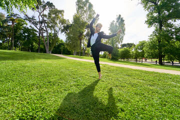 young man jumping and dancing contemporary ballet in the park with urban costume.