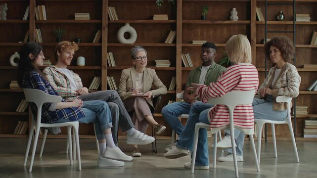 In a contemporary setting, six diverse young adults convene in a circle for a therapeutic session, fostering growth and solidarity