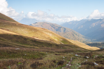 Fototapeta premium Grass-covered slopes of Caucasus mountains in the Republic of Adygea lit by the evening sun, Russia