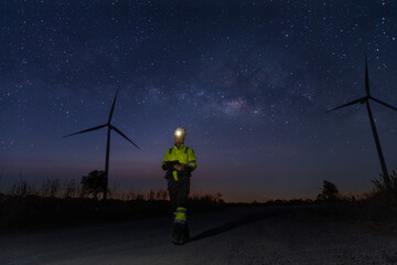 Obraz premium Survey Team Alternative energy for future at night for inspector safety. Engineers survey and checking wind turbines at milky way background. Wind Turbine Renewable energy technology