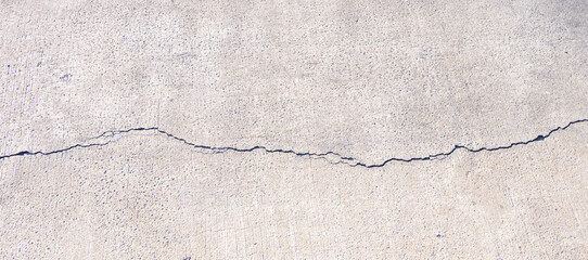 The old damaged concrete road texture background with long broken crack line on surface, High angle...