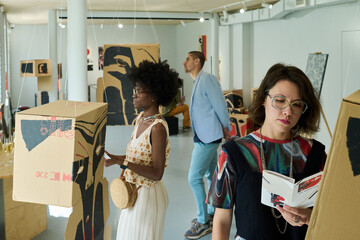 Group of young intercultural visitors of modern art gallery attending new exhibition with variety of expositions
