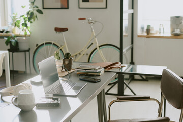 High angle shot o empty workspace equipped with desk, laptop and office supplies, pastel yellow...
