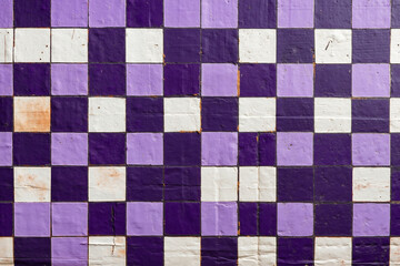 A purple and white checkered wall with peeling paint on it