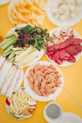 Served table with many products: sausage, bacon, salted fish, greens, sliced oranges and lemons, and other products. Concept of tasty and healthy food. Top view.