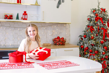 Smiling Girl Holding Christmas Gift Box. A cheerful girl holding a red Christmas gift box in a...