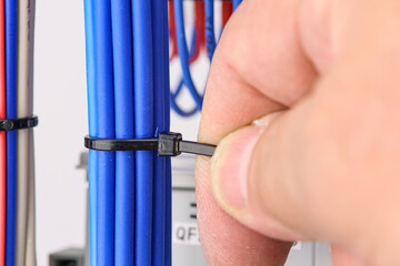 Installation of a plastic ties on electrical insulated mounting wires. Close-up. Soft focus.