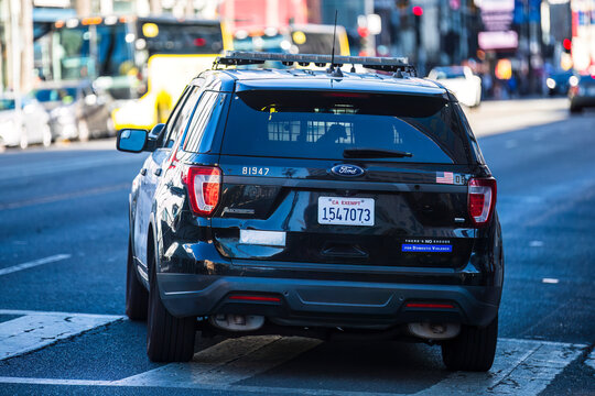 Rear view of an LAPD patrol SUV on a busy Los Angeles street, featuring public awareness decals.