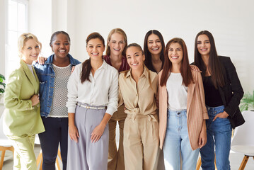 Portrait of a group of happy cheerful young diverse women coworkers or company employees looking at camera posing and smiling together standing in a row in office. Business people concept.