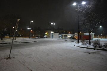 The city of Varkaus, Finland with houses, street lighting, shops, shops, parking lots, cars and trees stands in white snow. The Finnish central street is decorated for the celebration of the New Year,