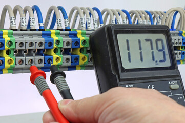 Measurement of electrical parameters in a switchboard using a multimeter.
