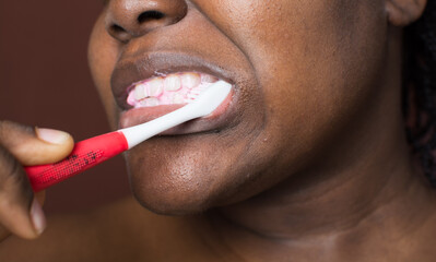 Brown skin woman brushing her teeth, woman practicing oral dental hygiene, using a tooth brush to clean teath