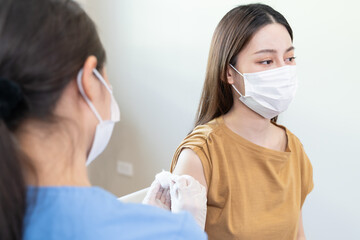 People getting a vaccination to prevent pandemic concept. Woman in medical face mask  receiving a...