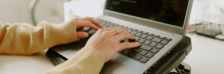 Website banner with unrecognizable female hands typing on keyboard of laptop on cooling pad © AnnaStills