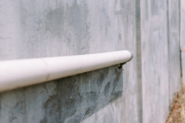 A PVC pipe connected to a house, serving as a drainage or utility conduit,
