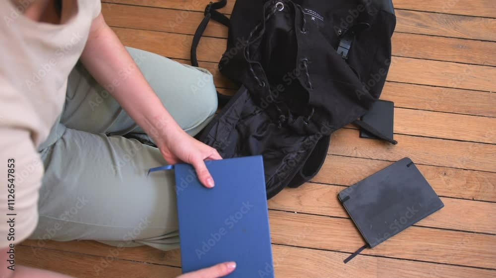 Poster a person is putting notebooks and a booklet in a backpack - slow motion