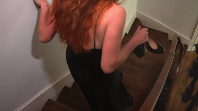 A Barefoot Woman Holding Her Shoes is Quietly Descending the Stairs - Slow Motion