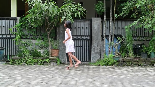 Cheerful Asian Indonesian little girl balances on stilts, joyful childhood moment that embodies the rich cultural heritage of Java. This traditional game usually called egrang