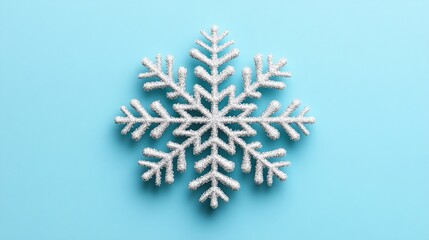 A delicate glittering white snowflake on a light blue background.