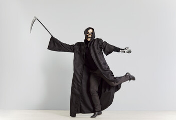 Grim reaper, holding a scythe and wearing a skeleton halloween mask, dancing on a grey background....