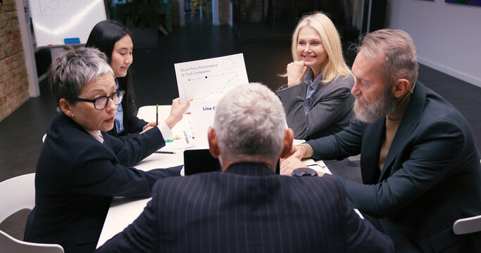 Diverse businesspeople discuss financial reports in office - Powered by Adobe