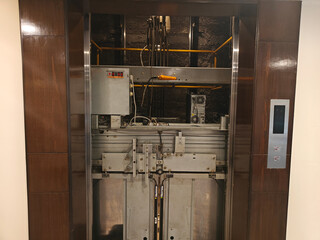Maintenance work reveals the inner machinery of a sleek elevator in a contemporary building during daytime