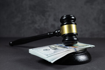 Judge's gavel and 100 american dollar banknotes on dark background