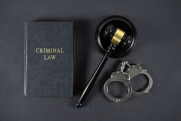 Law book, judge's gavel and handcuffs on gray textured table